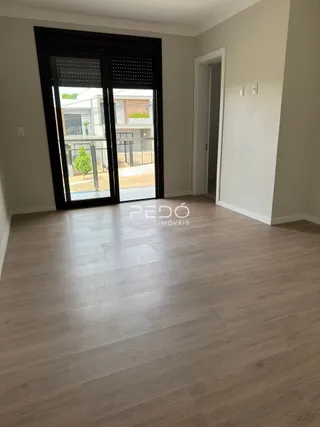 Interior com piso de madeira e portas de vidro grandes em uma residência.