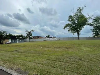 Campo gramado com árvores e construções ao fundo