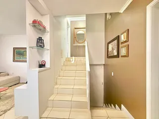 Uma foto mostra um corredor com escadaria em uma residência.
