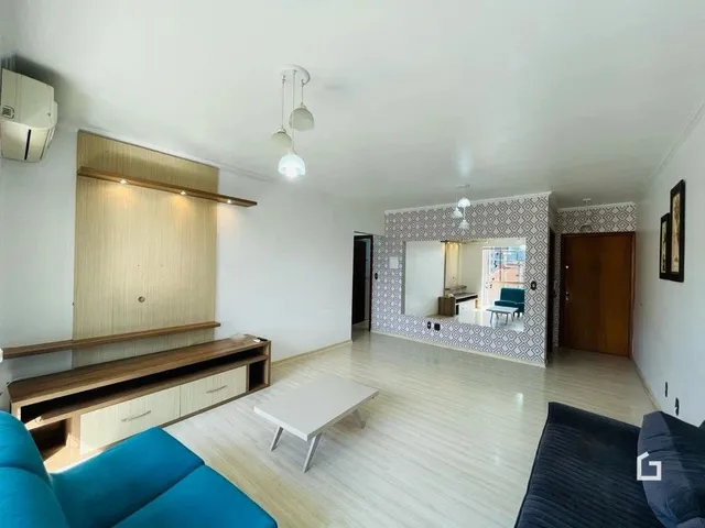 Sala de estar com piso de madeira clara e painel de madeira na parede.
