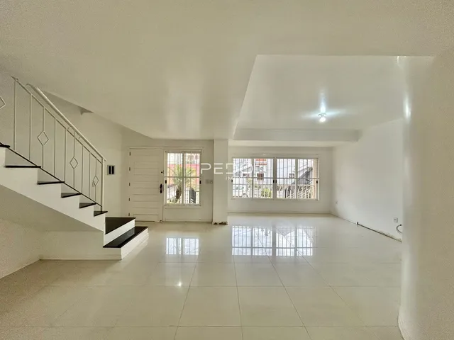 Interior de um grande hall com escadaria e piso de cerâmica em uma residência.