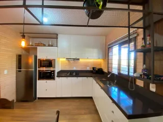 Foto interna de uma cozinha com armários brancos e bancada escura.