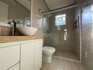 Interior de um banheiro com box de vidro e piso de cerâmica.