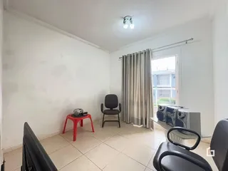 Sala de estar com paredes brancas e piso de cerâmica.