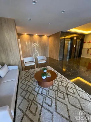 Sala de estar com sofá claro e piso de carpete geométrico.