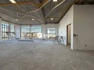 Foto de um espaço interno amplo e em construção com estrutura de concreto aparente.
