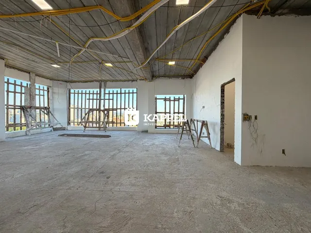 Foto de um espaço interno amplo e em construção com estrutura de concreto aparente.