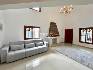 Sala de estar ampla com sofá cinza e piso claro.