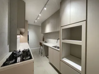 Cozinha moderna com armários claros e bancadas em tons neutros.