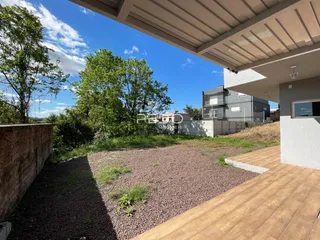 Vista externa do imóvel mostrando um pátio com deck e área de jardim.