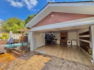 Fachada de uma casa com área coberta e piscina no quintal.