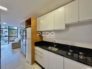 Vista da cozinha com armários brancos e bancada escura.
