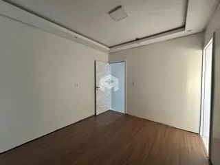 Interior de uma sala com piso de madeira e paredes brancas.