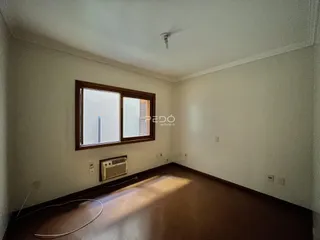 Interior de uma sala com piso de madeira e janela.
