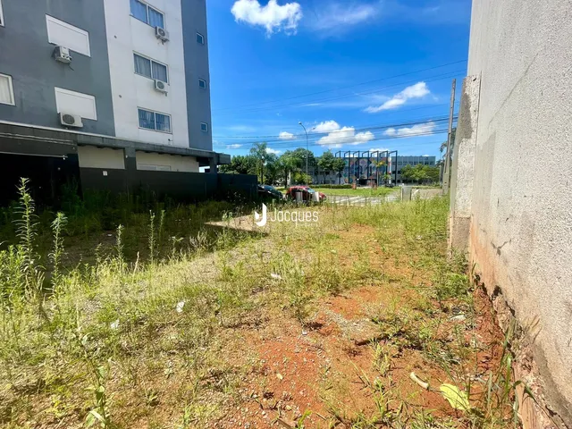 Vista externa de um terreno com vegetação alta ao lado de um edifício.