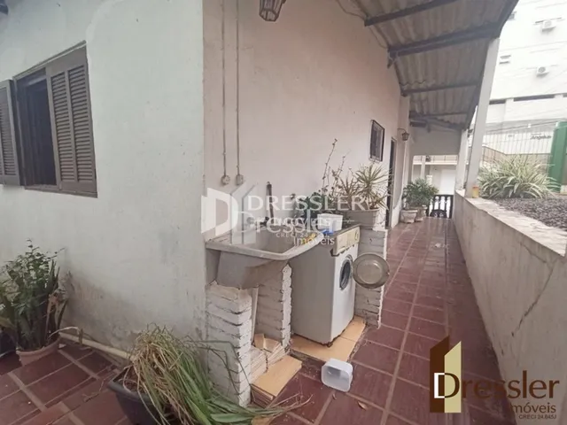 Vista externa de um pátio com piso de tijolo e vegetação.