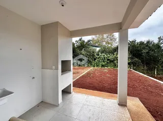 Vista externa de uma área pavimentada com parede e coluna de concreto.