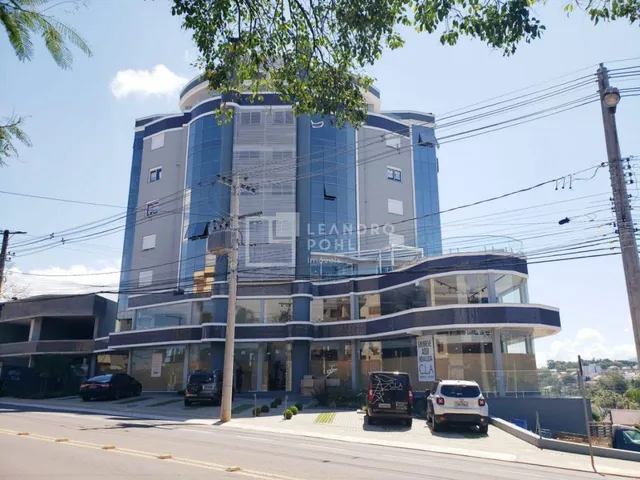 Fachada moderna de um edifício residencial em Lajeado, Brasil, com revestimento em vidro e painéis claros.