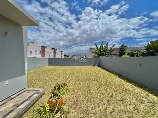 Vista de um quintal gramado cercado por um muro alto.