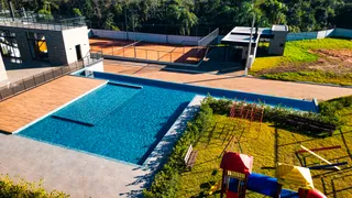 Vista aérea da piscina e área externa com gramado e quadra esportiva.