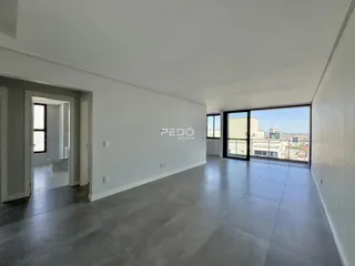 Ambiente interno de uma sala ampla com piso de cerâmica e vista para a cidade.