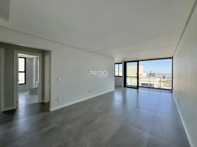 Ambiente interno de uma sala ampla com piso de cerâmica e vista para a cidade.