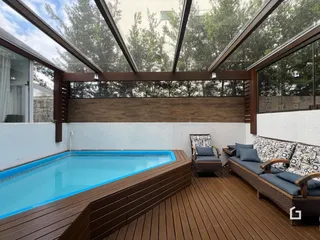 Foto de uma piscina externa com deck de madeira e área de estar.