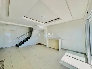 Sala de estar com piso de cerâmica e escadaria em um imóvel.
