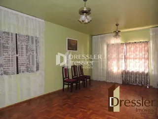 Sala de estar com piso de madeira e cortinas claras.