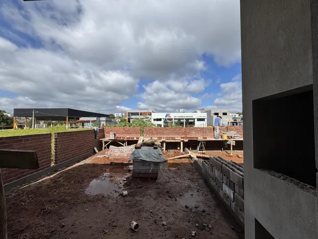 Vista externa de um terreno em construção com paredes de tijolo aparente.