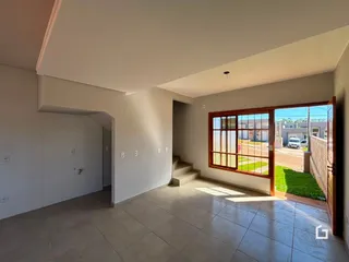 Vista interna de uma sala com piso de cerâmica e porta de vidro que dá para o exterior.