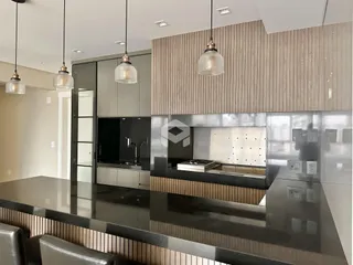 A cozinha moderna exibe armários escuros e uma ilha com bancada escura.
