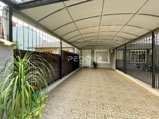 Vista de uma área coberta com piso de cerâmica e grade metálica em um imóvel.