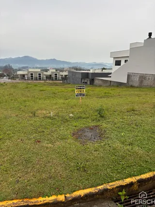 Vista externa de um terreno com grama verde e um edifício branco ao fundo.