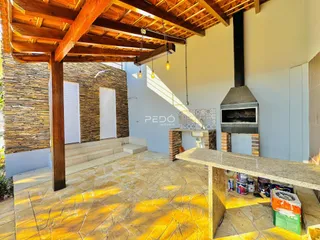 Área externa com parede de pedra e piso de cerâmica amarela.