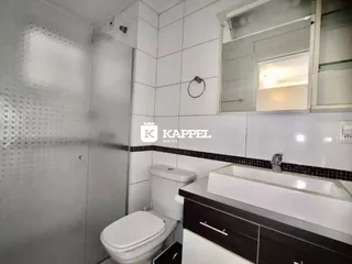 Banheiro com revestimento de azulejos brancos e bancada de mármore escuro.