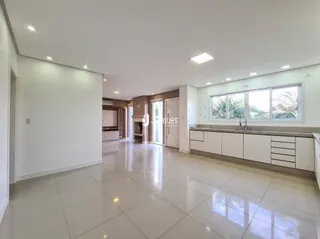 Ambiente interno de uma sala ampla com piso claro e paredes brancas.