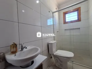 Banheiro com pia branca e vaso sanitário em ambiente revestido de azulejos brancos.