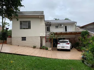 Fachada de uma casa em Lajeado, Brasil, com jardim e área pavimentada na frente.