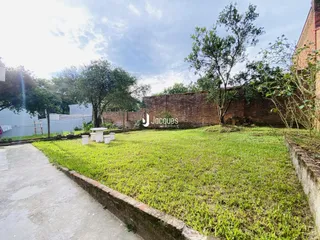 Área externa com gramado e muro de tijolos no lote.