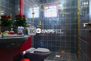 Foto interna de um banheiro com revestimento de azulejos escuros e janela.