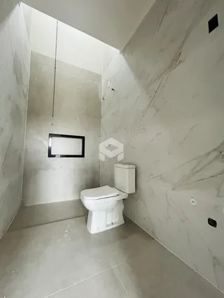 A foto mostra o interior de um banheiro com paredes brancas e piso claro.