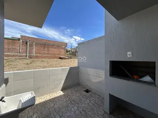 Vista externa de um pátio com piso de cerâmica e parede de tijolos no fundo.