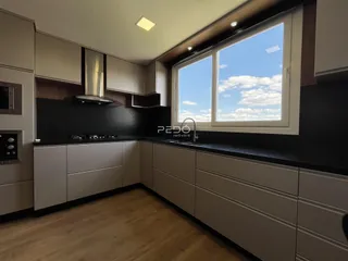 A cozinha moderna apresenta armários e bancadas em tons neutros.
