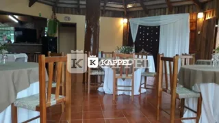 Ambiente interno com mesas e cadeiras de madeira em uma sala de jantar.