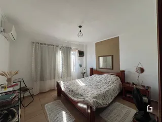 Quarto com cama de madeira e cortinas brancas em um imóvel no Brasil.