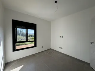 Ambiente interno com parede branca e grande janela com vista para a vegetação externa.