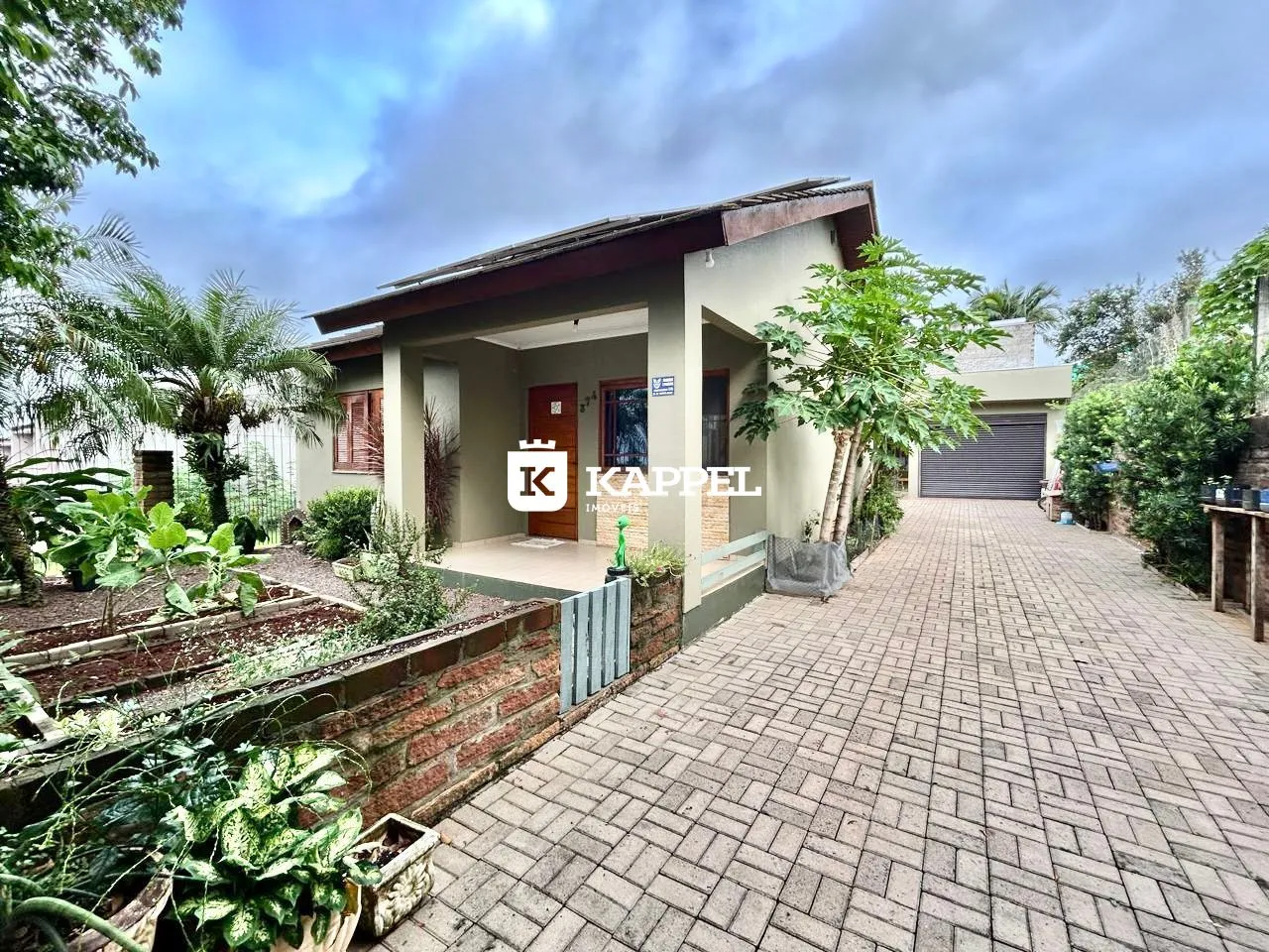 Fachada de uma residência com jardim e acesso pavimentado.