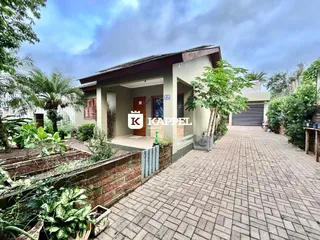 Fachada de uma residência com jardim e acesso pavimentado.
