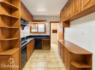 Foto interna mostrando armários de madeira em uma cozinha com piso de cerâmica.